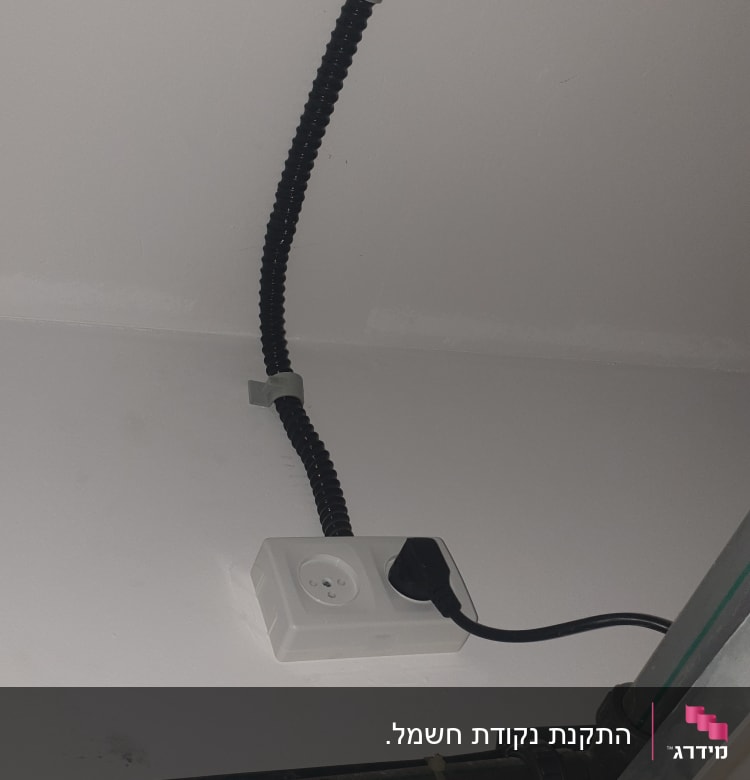 שקע חשמל עם תקע מחובר, כבלים על הקיר